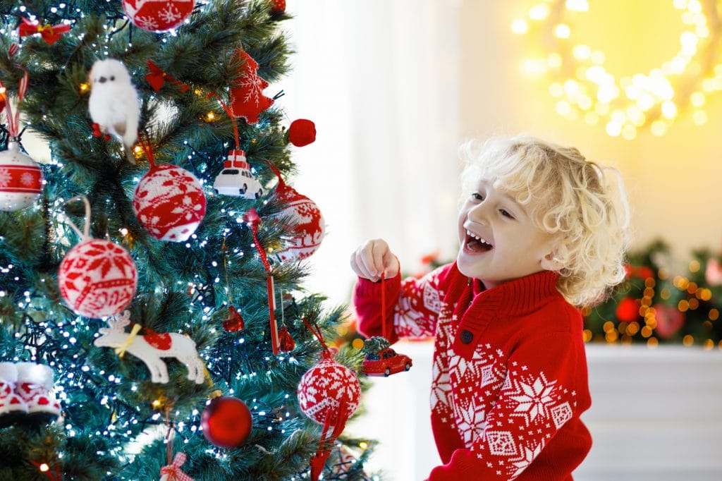 Child decorating Christmas tree. Kid on Xmas eve with Elf on the Shelf