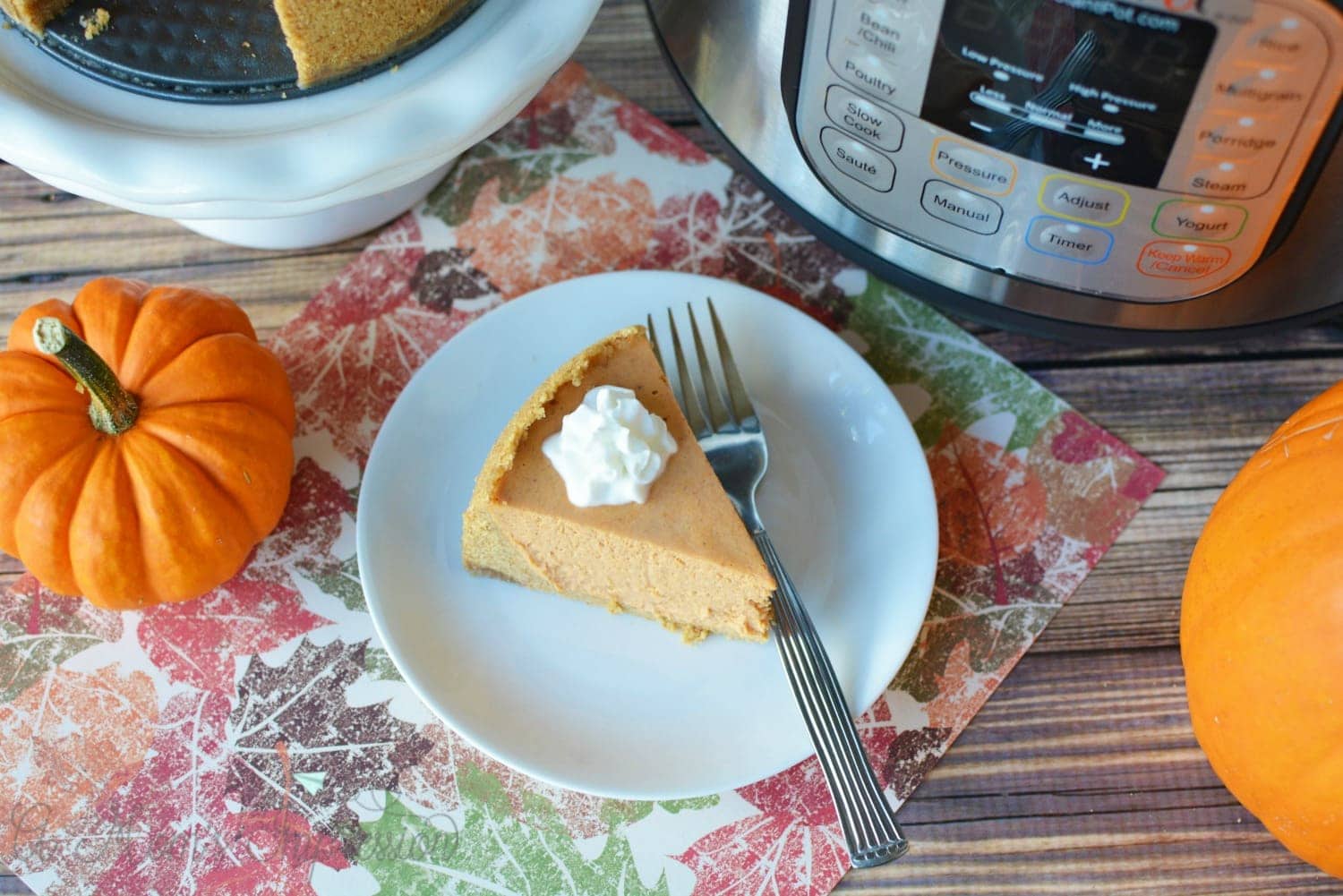 Pumpkin Cheesecake on a plate sitting next to an Instant Pot. 