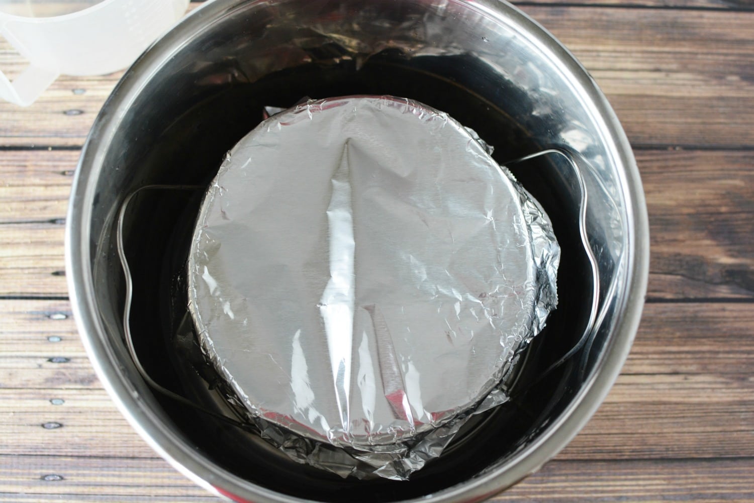 adding water to the bottom of the instant pot pan to cook cheesecake. 