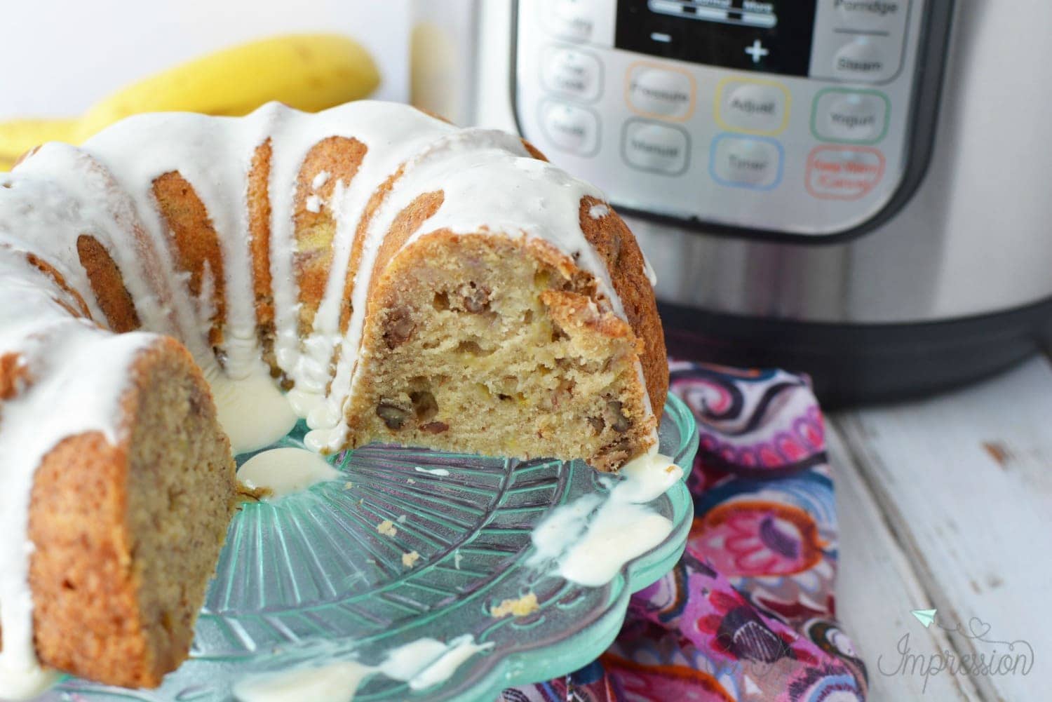Instant Pot banana bread sitting on a plate next to a pressure cooker.