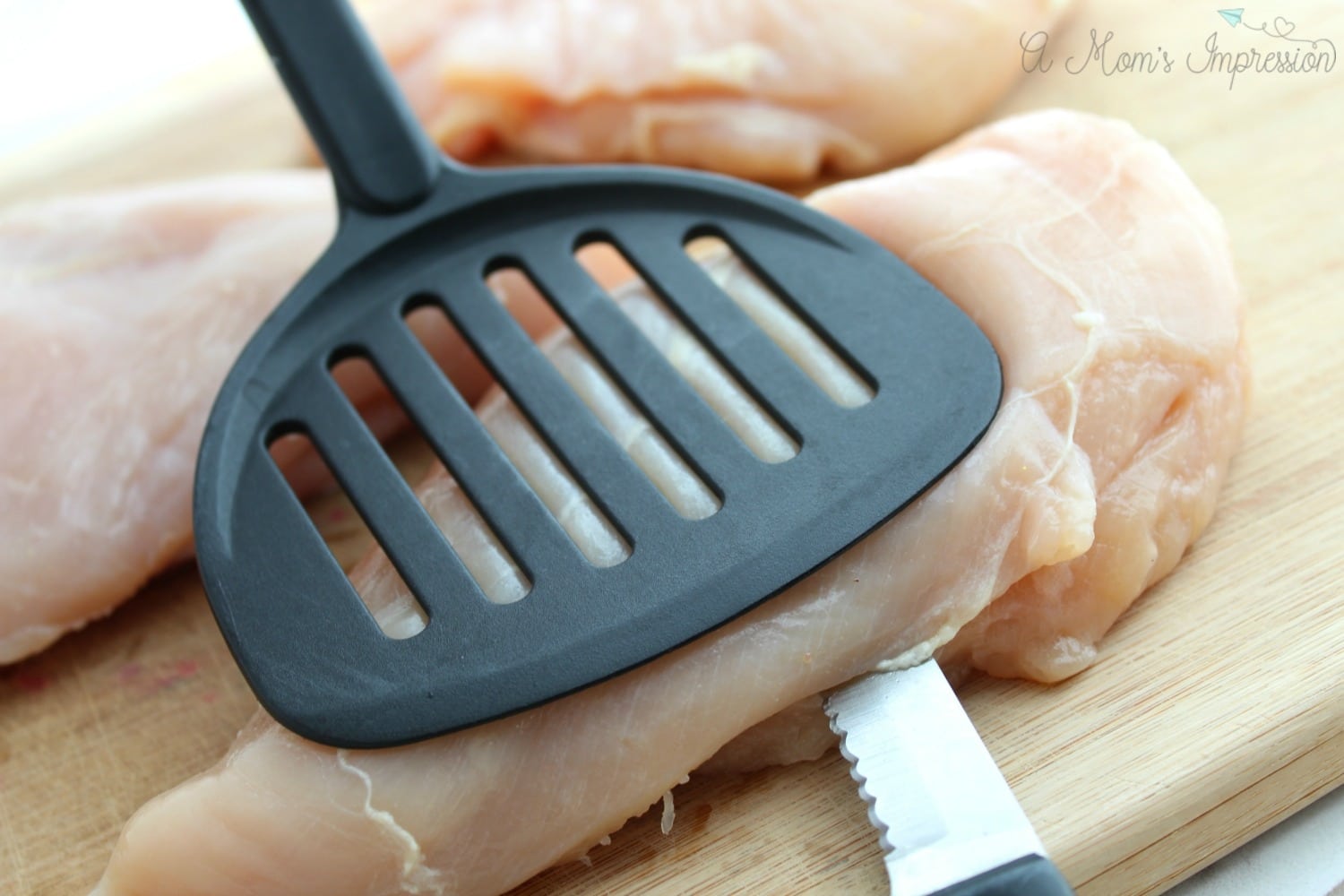 Cutting a pocket into a chicken breast using a spatula.