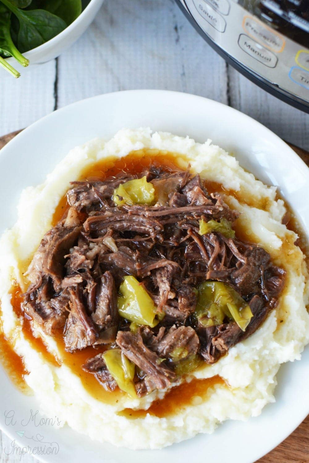 instant pot mississippi pot roast sitting on a plate next to a pressure cooker.