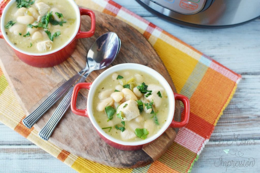 white bean chicken chili recipe in two red bowls on top of a cutting board