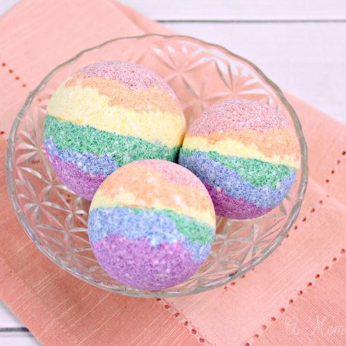 Three DIY rainbow bath bombs sitting in a bowl on a table