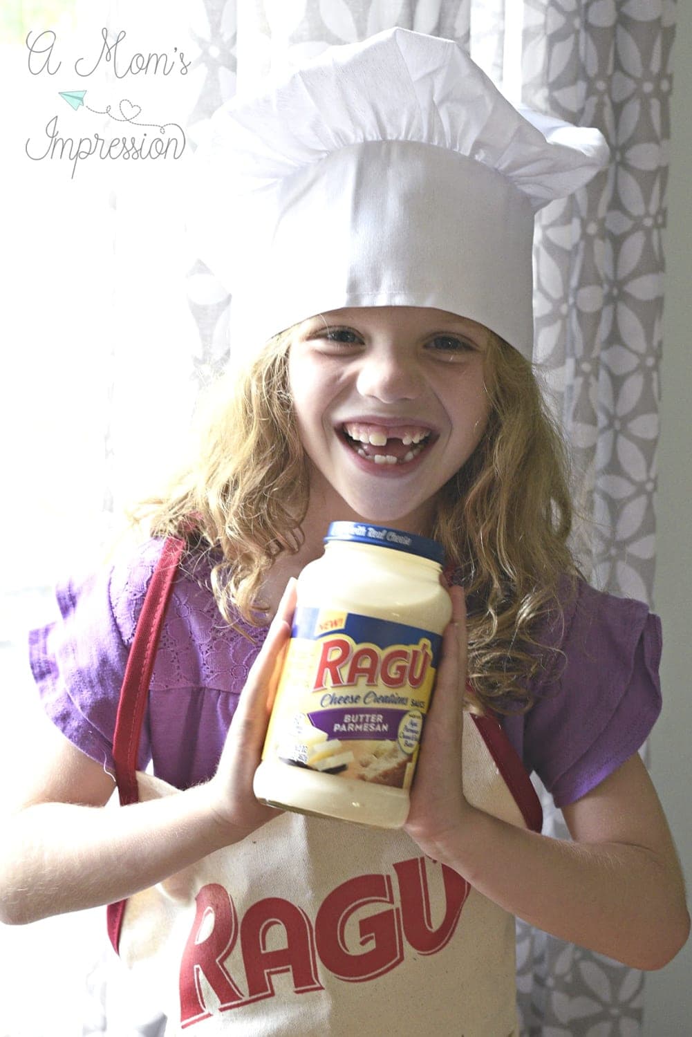 child wearing ragu apron and a chefs hat with a bottle of ragu sauce in her hands