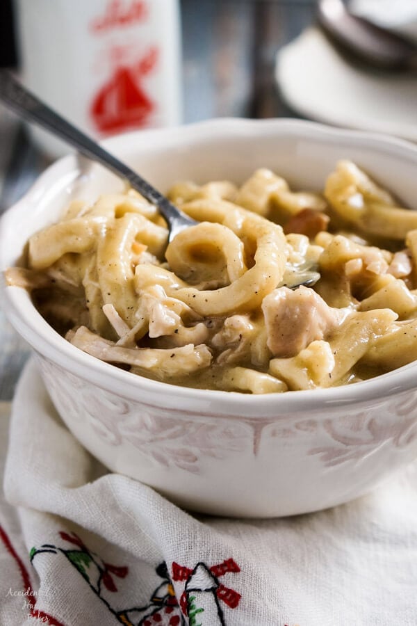 turkey and noodles in a white bowl sitting in front of a pressure cooker