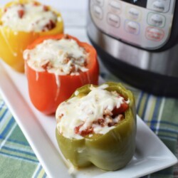 Instant Pot Sausage stuffed peppers on a white plate with a pressure cooker in the background