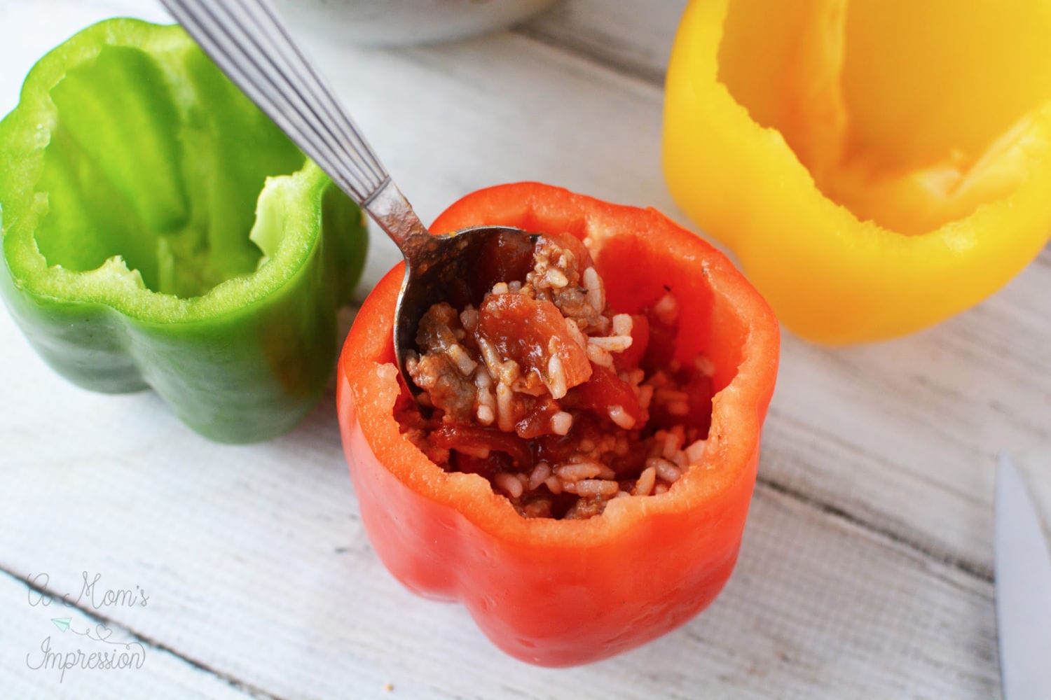 a fork pushing down mixture into a stuffed pepper 