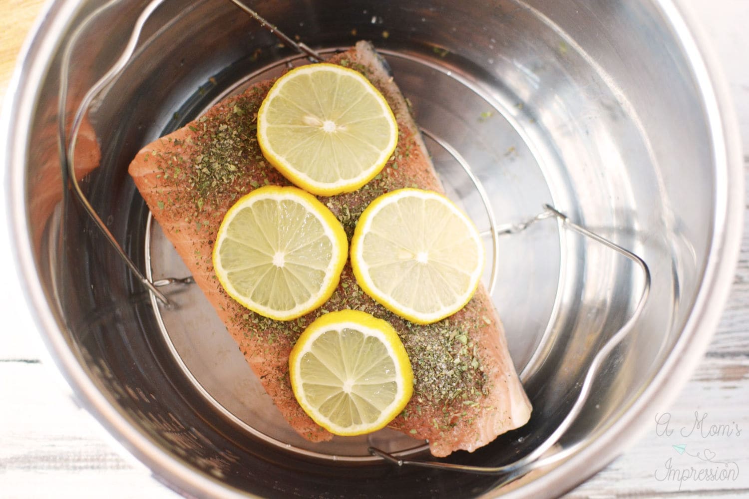 a piece of salmon in a pressure cooker pot with some sliced lemons on top