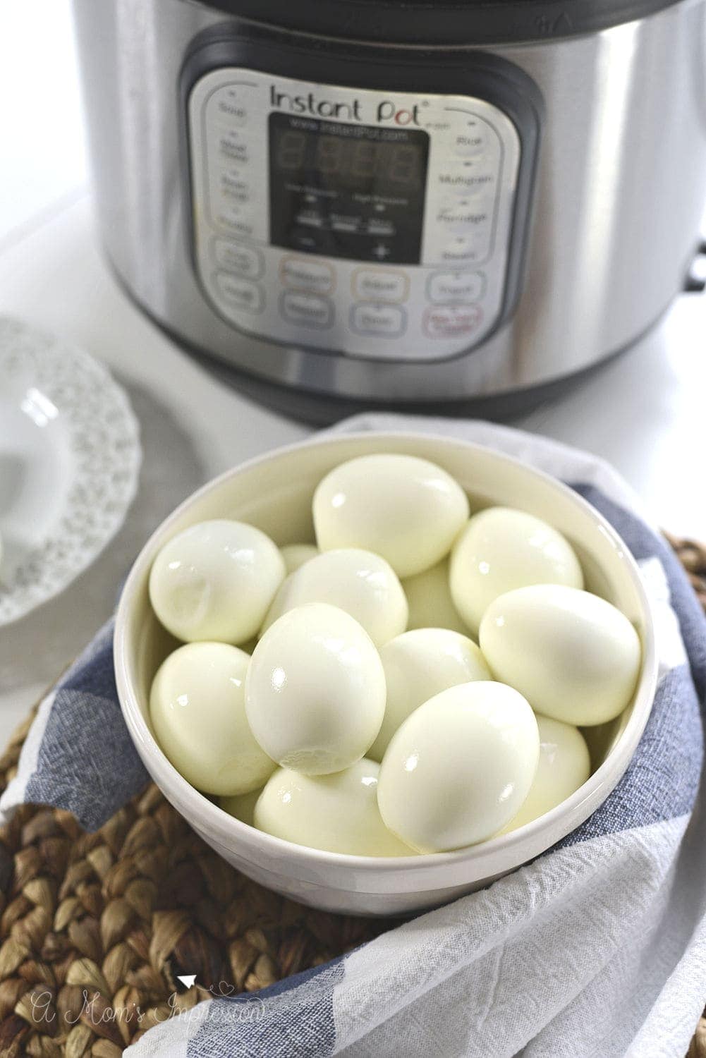 A bowl of hard boiled eggs sitting in front of an Instant Pot pressure cooker