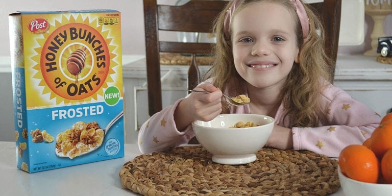 a girl smiling a she is eating breakfast cereal