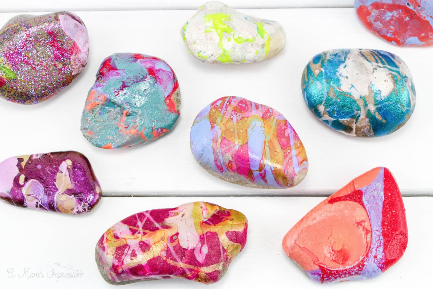 several painted rocks sitting on a white wood background