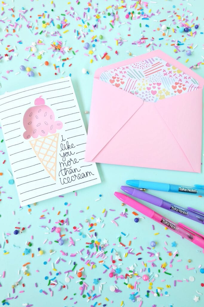 an ice cream card with a pink envelope with some markers