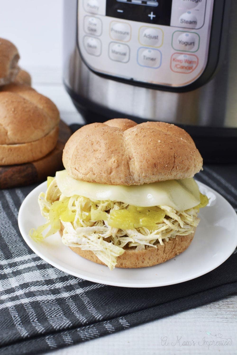 a Instant Pot Mississippi Chicken sandwich sitting in front of a pressure cooker
