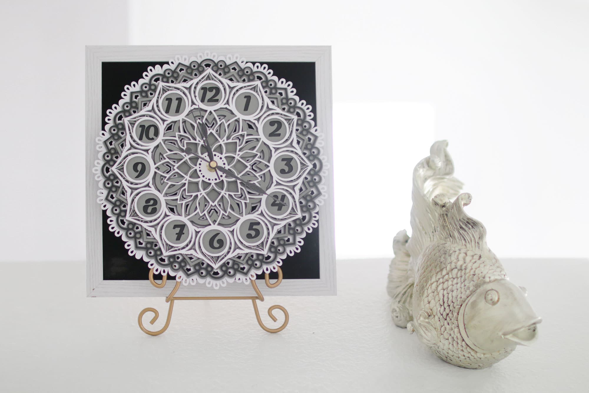 a homemade Mandala clock sitting on a table next to a ceramic fish