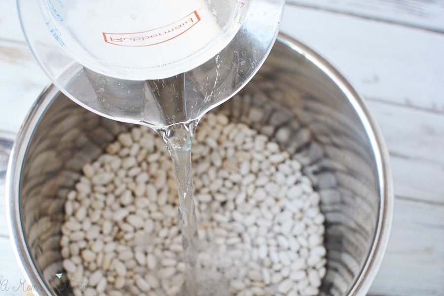 some water being poured into a pot full of white beans
