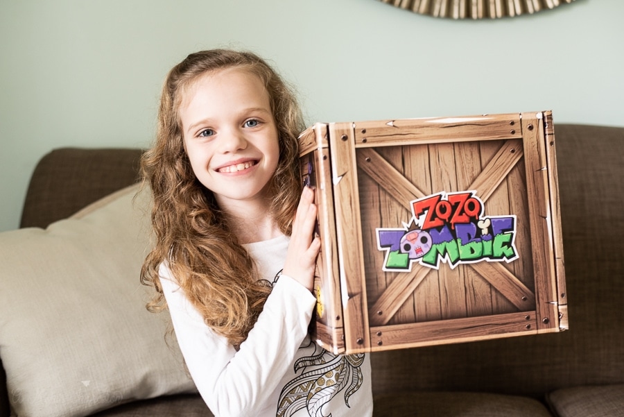 a girl holding up a box that says zo zo zombie on it