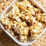 a bowl of carmel corn with almonds in it sitting on a table