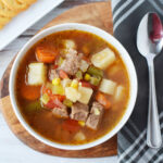 Instant Pot Vegetable Beef Soup served in a white bowl with spoon.