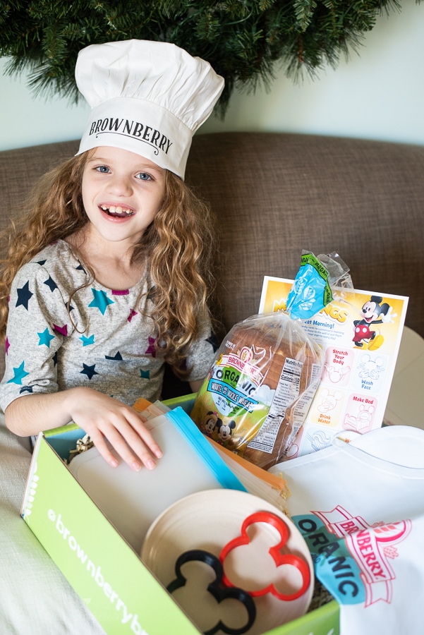 a girl with a box of goodies wearing a chefs hat