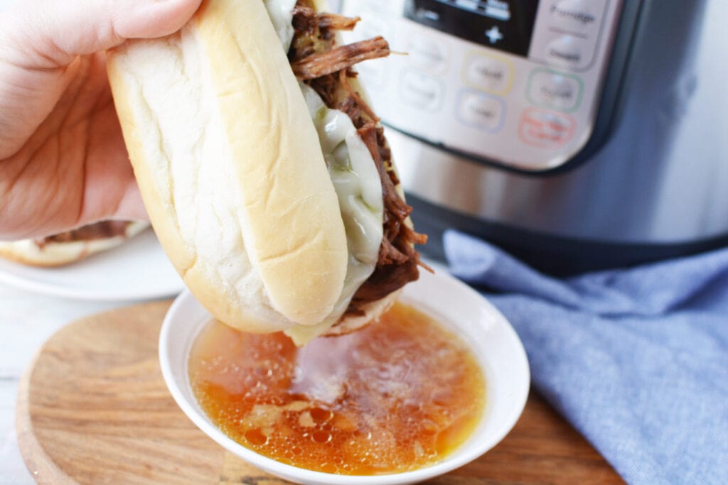 Instant Pot French Dip being dipped in au jus. 