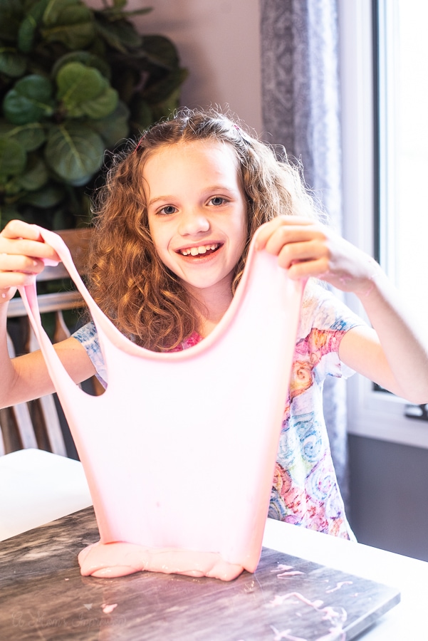 a girl stretching and holding up pink slime