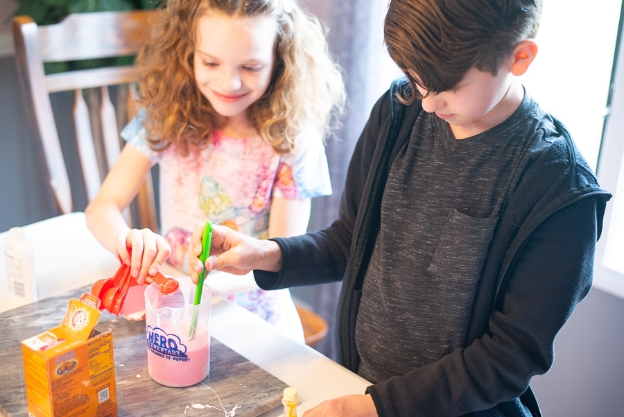 a boy and a girl mixing up glue and water for slime