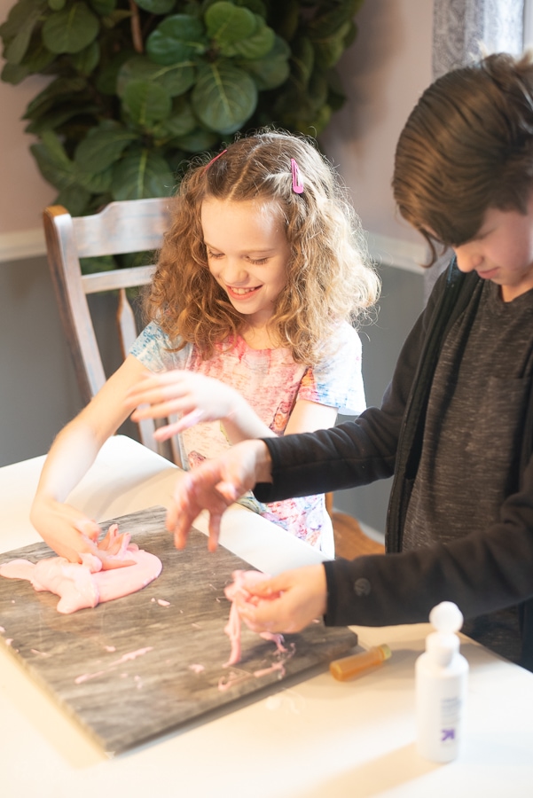 two kids playing with some pink goop on a table