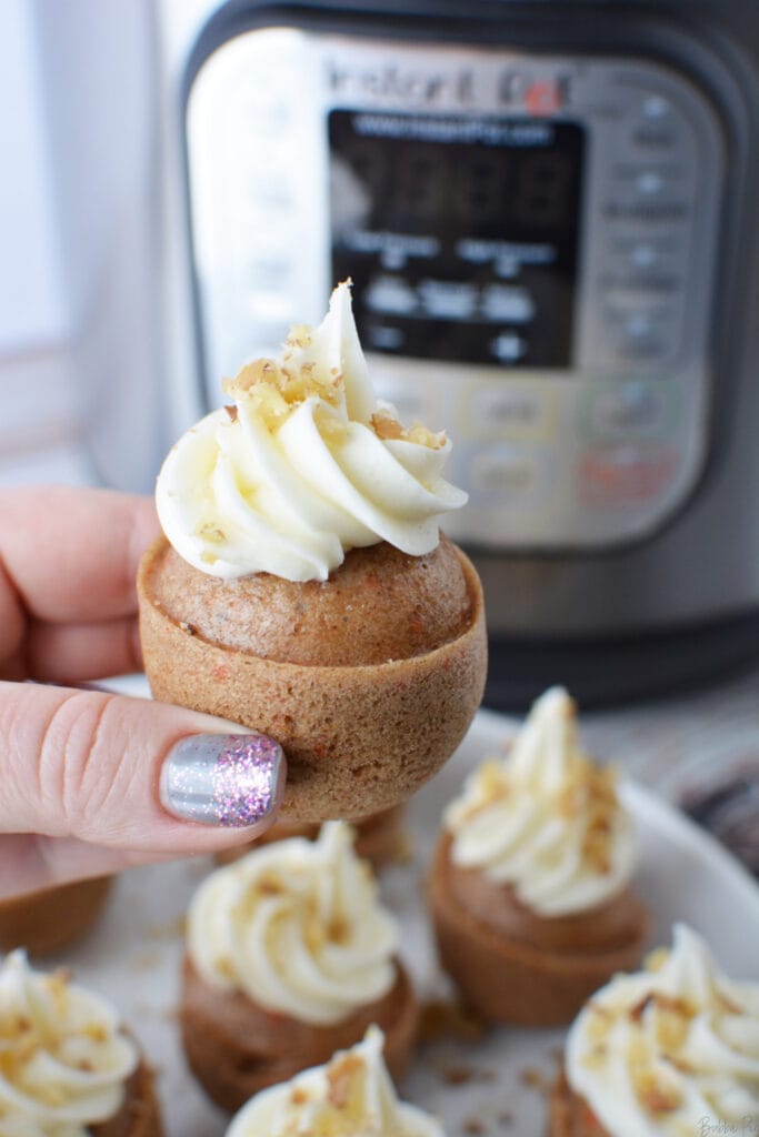 Instant Pot Carrot Cake Mini Bites being held with a pressure cooker in the background.