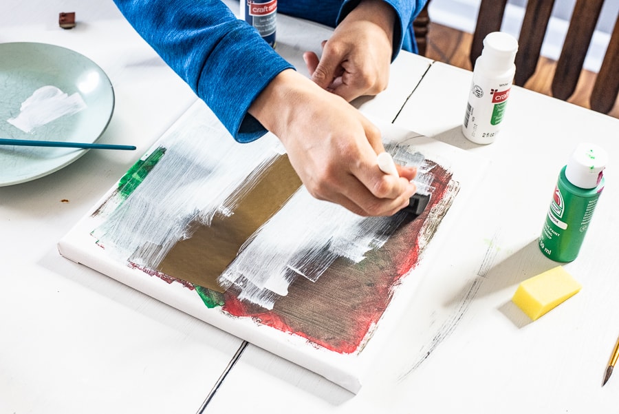 a boy painting white all over a canvas