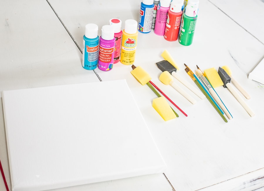 a canvas, paints and paintbrushes on a table