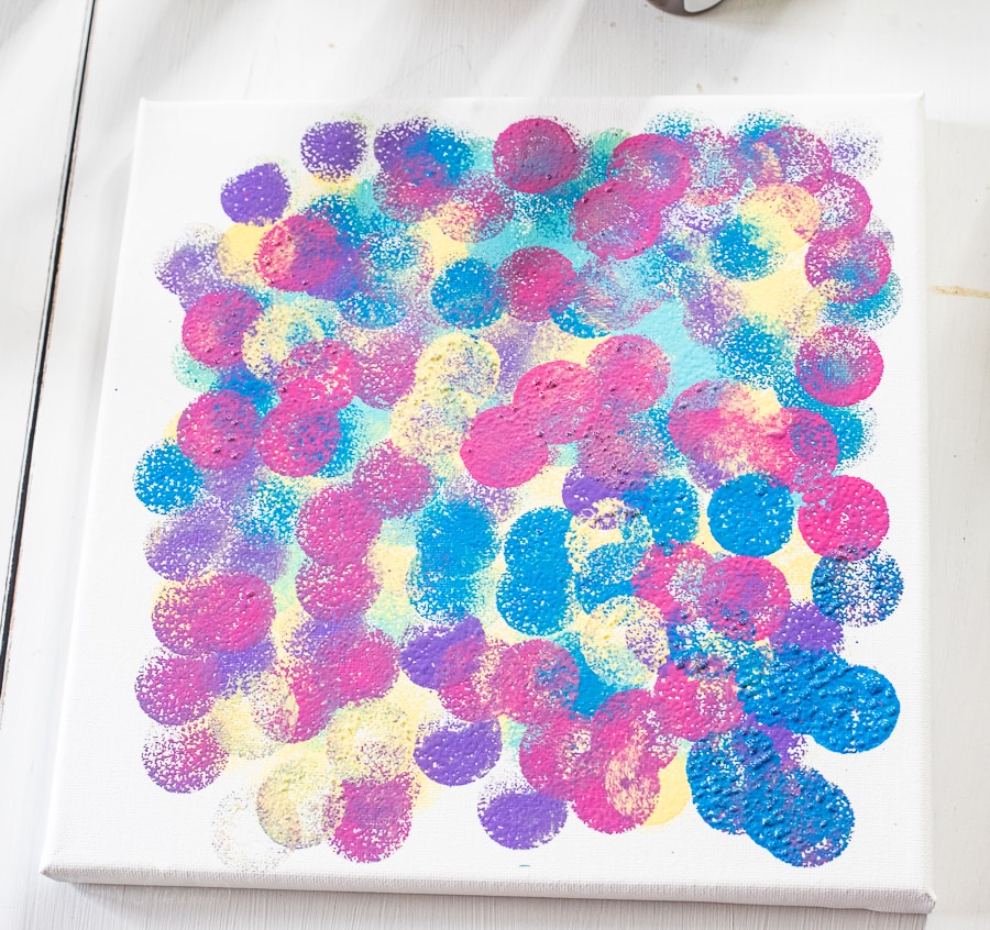 a bunch of colorful dots painted on a canvas