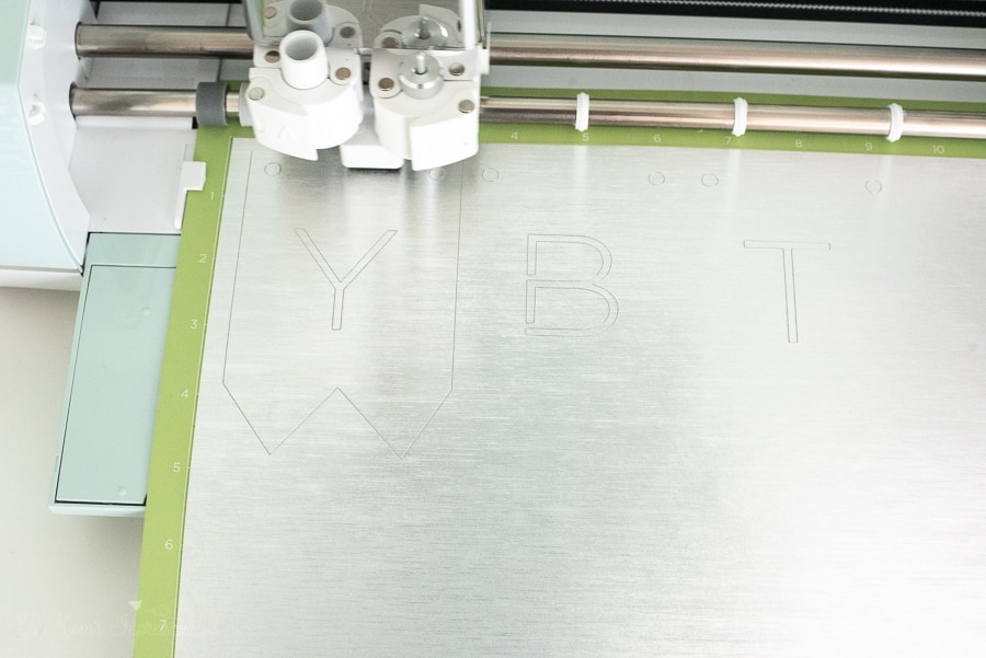 a Cricut Cutting machine cutting out a silver piece of cardstock 