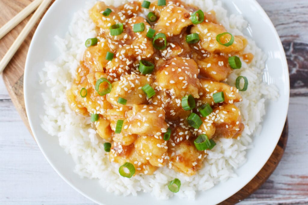 Pressure Cooker General Tso's Chicken on a white plate with chop sticks.