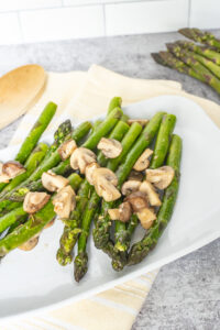 a white platter with asparagus with mushrooms