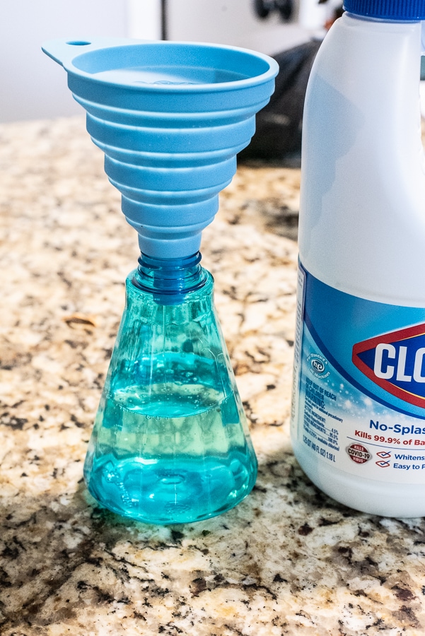 Bleach being poured in a spray bottle through a funnel