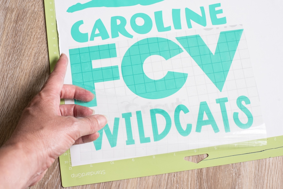 a person weeding out vinyl from a design that says FCV