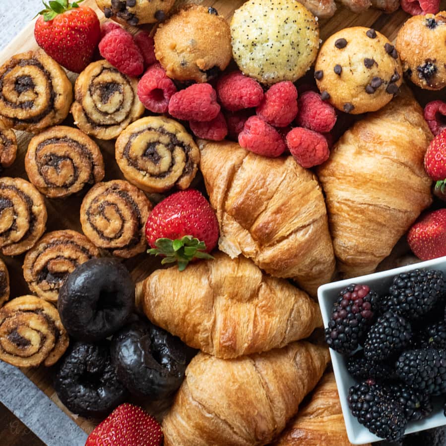 a lot of breakfast foods and fruit displayed on a cutting board