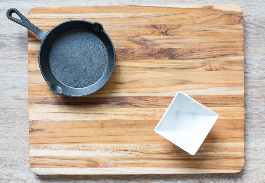 a small cast iron pan and a bowl on a cutting board