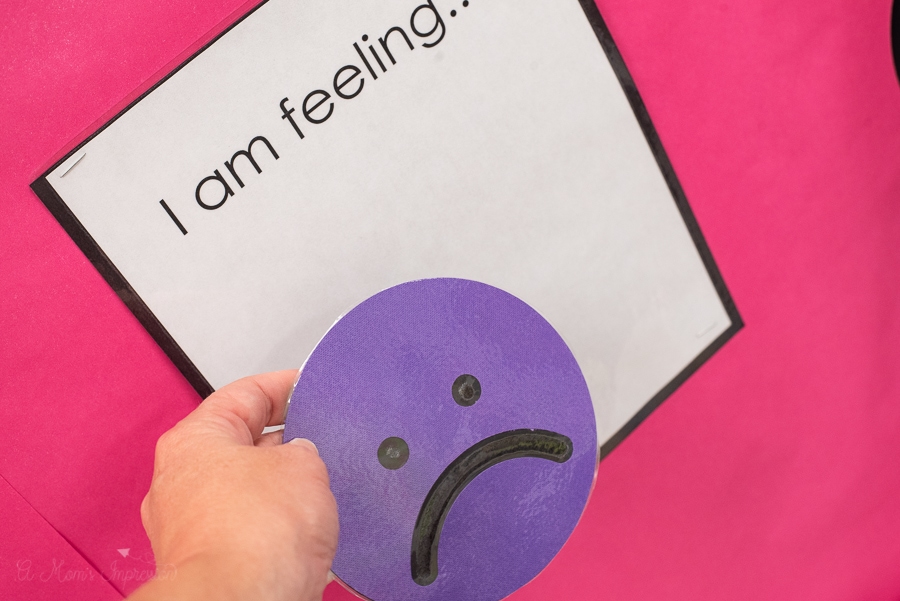 a purple frowny face being placed on a board that says I am feeling...