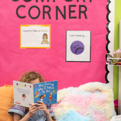 a girl reading a book sitting on pillows in a calming corner