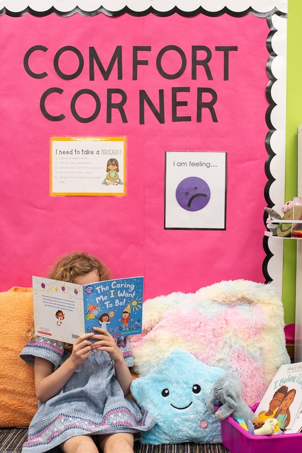 a girl reading a book sitting on pillows in a calming corner