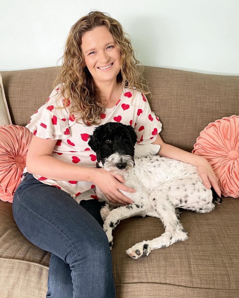 woman cuddling with a dog on a sofa